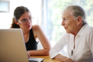 Beratungssituation zwischen junger und alter Person am Laptop